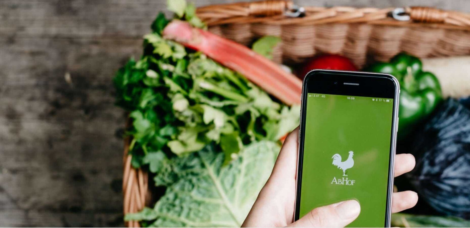 Die Abhof App im Fokus mit Gemüse im Hintergrund