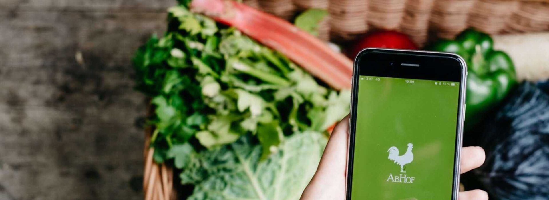 Die Abhof App im Fokus mit Gemüse im Hintergrund