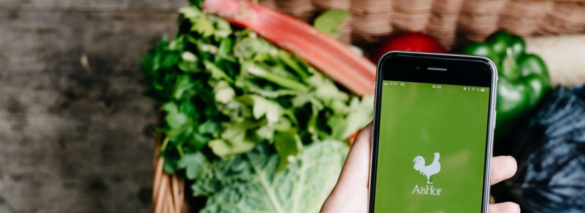 Die Abhof App im Fokus mit Gemüse im Hintergrund
